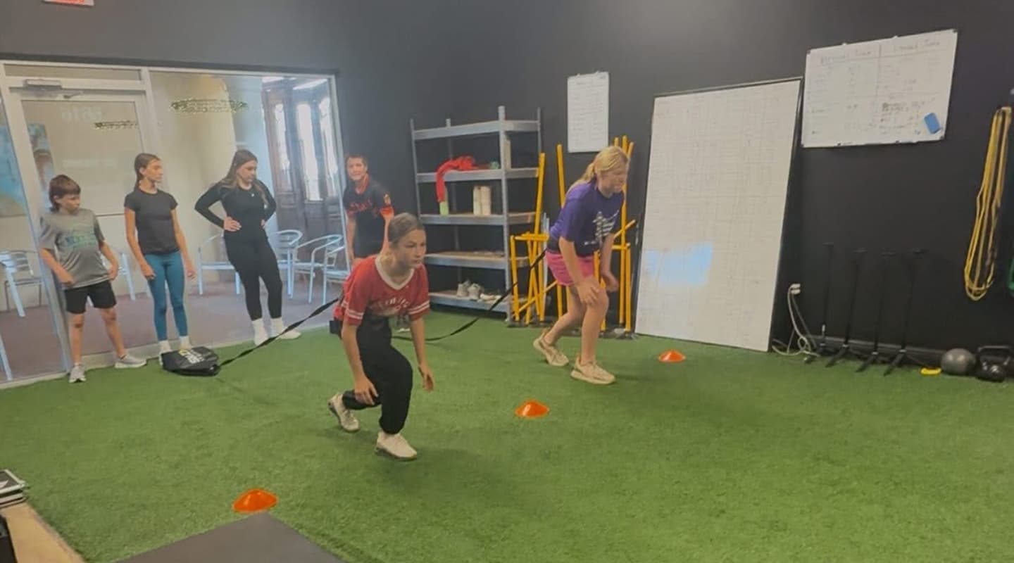 Young athletes doing a banded lateral drill on the turf